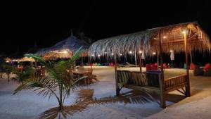 a pavilion with a bench and tables on the beach at night at Salabose Cottages in Gili Air