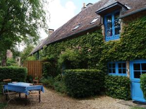 una casa con puertas azules y una mesa frente a ella en Gîte Fontenay-sur-Vègre, 3 pièces, 4 personnes - FR-1-410-275, en Fontenay-sur-Vègre