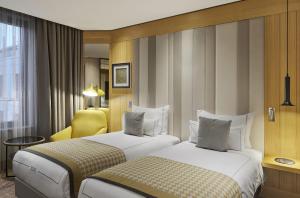 a hotel room with two beds and a yellow chair at TITANIC Chaussee Berlin in Berlin