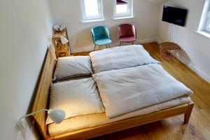 uma cama com lençóis brancos e duas cadeiras num quarto em Wyker Loft em Wyk auf Föhr