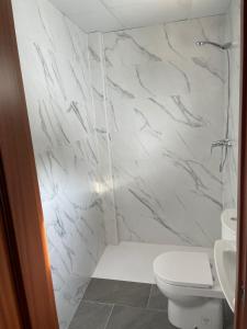 a white bathroom with a toilet and a shower at Hotel-Restaurante la Loma in Baeza