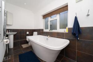 baño con bañera, lavabo y ventana en Luxury home in Gerrards Cross, en Chalfont Saint Peter