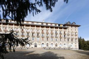 un grand bâtiment blanc avec des arbres devant lui dans l'établissement Appartement T2 Font Romeu, à Font-Romeu-Odeillo-Via