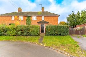 a red brick house with a gate and bushes at Luxury home in Gerrards Cross in Chalfont Saint Peter