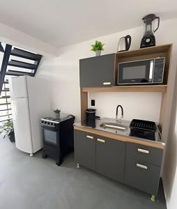 a kitchen with a sink and a microwave and a refrigerator at Lofts Meia Morada SFS in São Francisco do Sul +45 photos