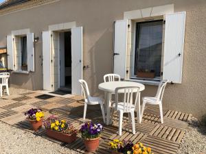 a patio with a table and chairs and flowers at Moulin Authentique avec Pêche, Animaux Acceptés et Confort Moderne près du Mans - FR-1-410-323 in Mézières-sur-Ponthouin