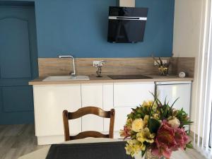 a kitchen with a sink and a table with a vase of flowers at Charmant gîte cozy près du Mans avec jardin, terrasse, proche commodités et activités. - FR-1-410-336 in Rouillon