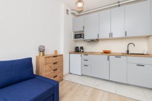 a kitchen with white cabinets and a blue couch at Studio Apartment near River and Park by Rent like home in Gdańsk