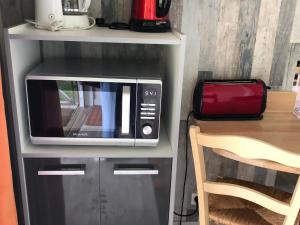 a microwave sitting on a shelf next to a table at Chalet nature et détente avec piscine, proche zoo de la Flèche et Le Mans, idéal cyclistes et familles - FR-1-410-367 in La Suze-sur-Sarthe +8 photos