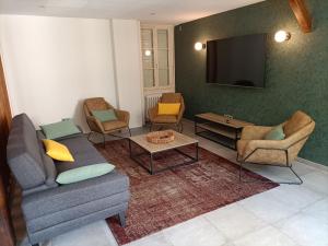 uma sala de estar com um sofá e cadeiras e uma televisão de ecrã plano em Gîte Bruère-Allichamps, 6 pièces, 10 personnes - FR-1-586-26 em Bruère-Allichamps