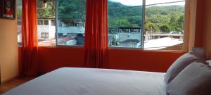 a bedroom with a bed and a large window at Aracari Inn Mindo in Mindo