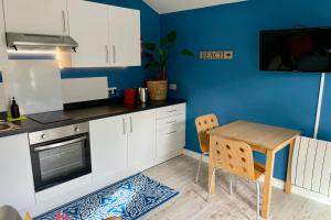 a kitchen with a table and a blue wall at Fistral Studio in Newquay