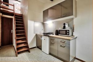 a small kitchen with a microwave and a staircase at Le Chaleureux Bressan in Bourg-en-Bresse