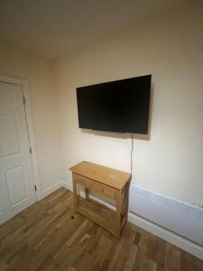 Elle comprend une télévision à écran plat murale et une table en bois. dans l'établissement 1 Bedroom Flat with Parking, à Leicester