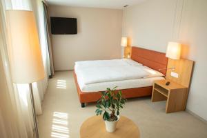 ein Schlafzimmer mit einem Bett und einer Topfpflanze in der Unterkunft OCHSEN LODGE by Ochsen Lenzburg in Lenzburg