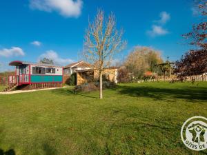 a tree in a yard in front of a house at Roulotte climatisée avec piscine et jardin - FR-1-622-54 in Vihiers
