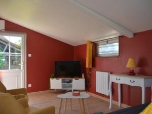 sala de estar con paredes rojas y TV de pantalla plana. en Gîte Roëzé-sur-Sarthe, 3 pièces, 6 personnes - FR-1-410-392, en Roézé-sur-Sarthe