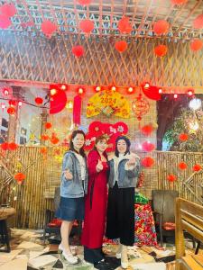 drie vrouwen staan voor een muur met rode harten bij Hang Mua Bungalow in Ninh Binh