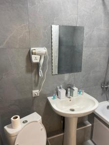 een badkamer met een wastafel, een toilet en een spiegel bij Good Home на 8 персон in Alma-Ata
