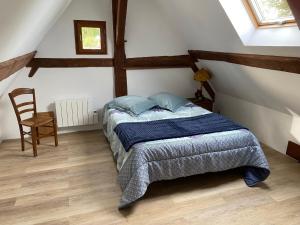 a bedroom with a bed and a chair in a attic at Gîte de charme au bord de l'eau, à 30min du Mans, cadre paisible avec pêche et randonnées à proximité - FR-1-410-414 in Congé-sur-Orne