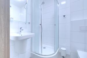 a white bathroom with a shower and a sink at Lawendowy Dwór in Pszczółki