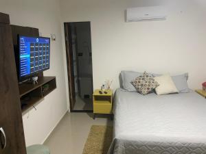 a bedroom with a bed and a flat screen tv at Casa pé na areia - Brandão House in Saco dos Cações