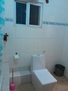 a white bathroom with a toilet and a window at Fayes Apartments in Brusubi