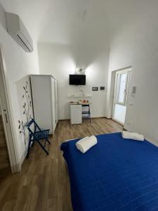 Dieses weiße Zimmer verfügt über ein blaues Bett und einen Schreibtisch. in der Unterkunft 67 Rooms in Cefalú