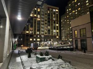 een stad 's nachts met sneeuw op de grond en gebouwen bij Good Home на 8 персон in Alma-Ata