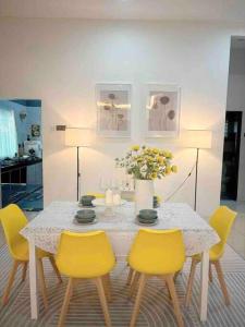 a dining room table with yellow chairs and a vase of flowers at Homestay taiping in Taiping