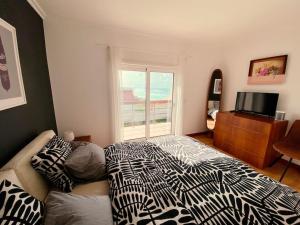 a bedroom with a bed and a television and a window at Casa da Brisa do Mar in Pataias +32 photos