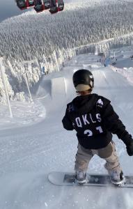 a man riding a snowboard down a snow covered slope at Ruka Park Base Camp in Ruka