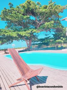una sedia in legno seduta accanto alla piscina di Casa pé na areia - Brandão House a Saco dos Cações