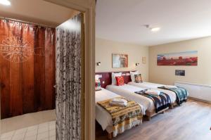 a bedroom with two beds and a sliding glass door at Hotel Le Ranch in Brûlon