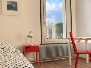 een slaapkamer met een raam en een rode tafel en stoel bij Gîte Virecourt, 4 pièces, 5 personnes - FR-1-584-46 in Virecourt