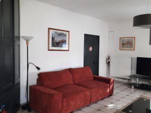 a red couch in a living room with a television at Charmant gîte de 160 m² dans une ferme près de Toul, à 30 min de Nancy, avec terrasse et jardin privé - FR-1-584-65 in Toul