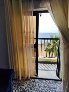a room with a door open to a balcony with the ocean at HOTEL DE L'OCEAN KRIBI in Kribi