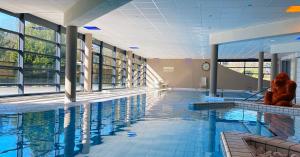 a swimming pool with two people sitting on the edge of it at Le Forges Hotel in Forges-les-Eaux