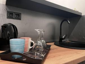 a kitchen counter with cups and glasses on a tray at Apartman ROYAL Bulevar in Zenica