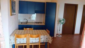 a kitchen with blue cabinets and a table and chairs at Beach Apartments Poseidon in Casa dello Stumio