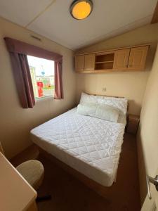 - un petit lit dans une petite chambre avec fenêtre dans l'établissement Bittern 8, Scratby - California Cliffs, Parkdean, sleeps 8, free Wi-Fi, bed linen and towels included, pet friendly - 2 minutes from the beach!, à Scratby