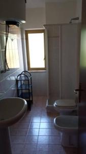 a bathroom with two sinks and a toilet and a window at Beach Apartments Poseidon in Casa dello Stumio