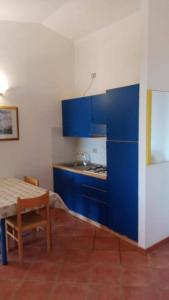 a kitchen with blue cabinets and a table in a room at Beach Apartments Poseidon in Casa dello Stumio