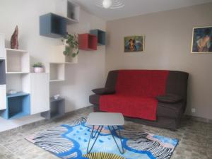 sala de estar con sofá y manta roja en Chez Anne et Aimé, en Millau