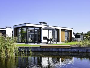 a modern house with a view of a pond at Holiday Home MarinaPark Nieuw Loosdrecht-1 by Interhome in Loosdrecht