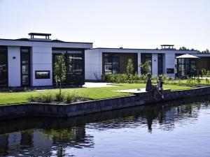 two people sitting on a bench next to a body of water at Holiday Home MarinaPark Nieuw Loosdrecht-1 by Interhome in Loosdrecht