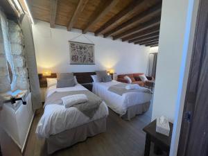 a hotel room with two beds and a couch at La Casa del Cantero in Pinilla del Valle