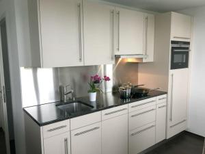 a white kitchen with white cabinets and a sink at Modern little gem close to lake Thun in Reutigen