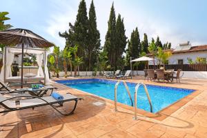 uma piscina com cadeiras, um guarda-sol e uma mesa em Villa Lara - 3bed Bangalow with Large Pool em Agia Napa
