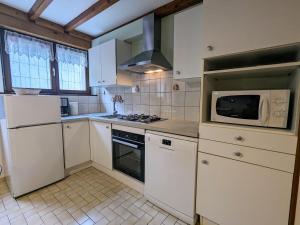 uma cozinha com armários brancos e um micro-ondas em Gîte La Bresse, 3 pièces, 4 personnes - FR-1-589-127 em La Bresse